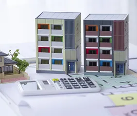 マンションの模型が二つ横並びに並んでおり、その手前に電卓が置かれている